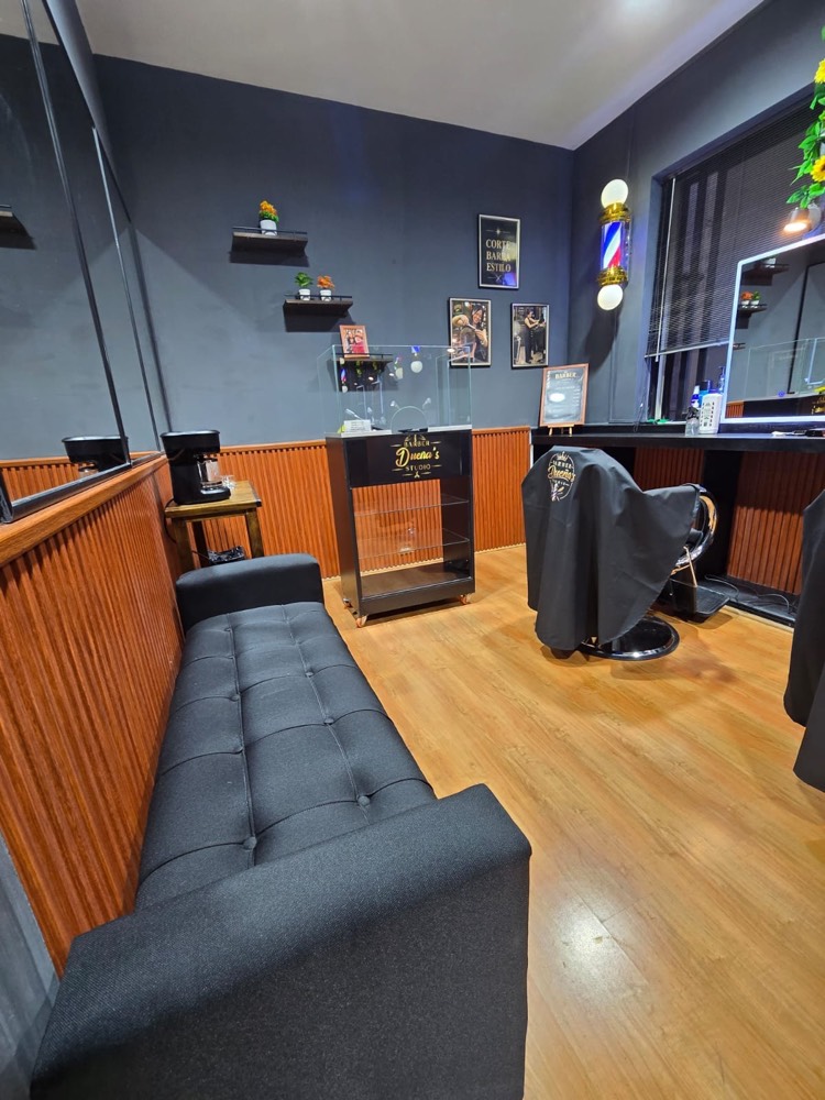 Sala de espera con sofá capitoné y vitrina de la barbería